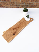 large elm charcuterie board with handle. white background with two succulents.