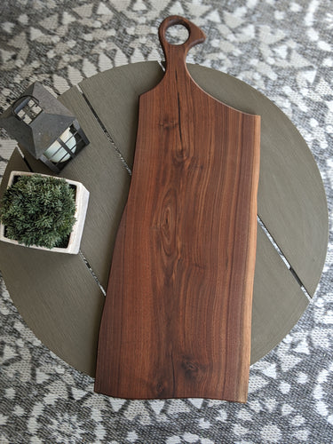 Dark walnut charcuterie board with goose neck handle. Charcoal epoxy accent.